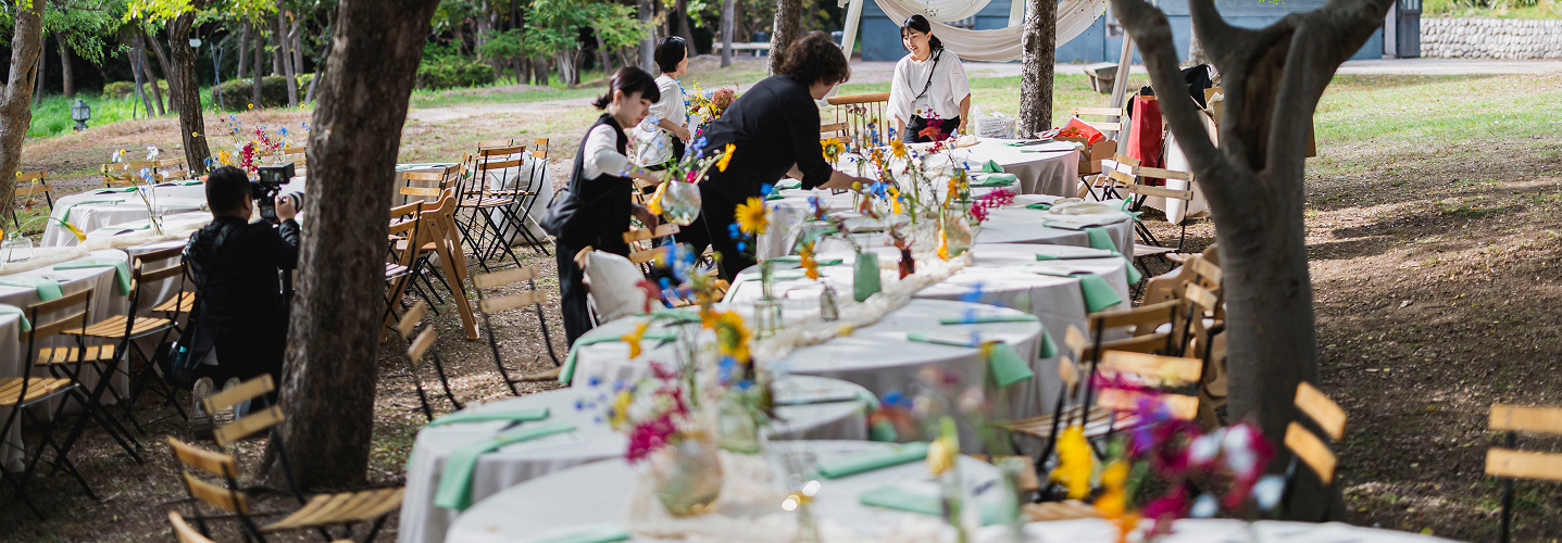 屋外のガーデンウェディング会場でスタッフがテーブルをセッティングしている様子