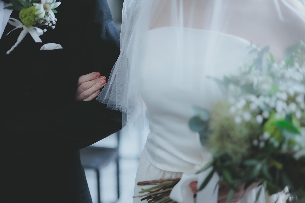 ゴールドの結婚指輪が2つ、グリーンの枝と一緒にテーブルに置かれている