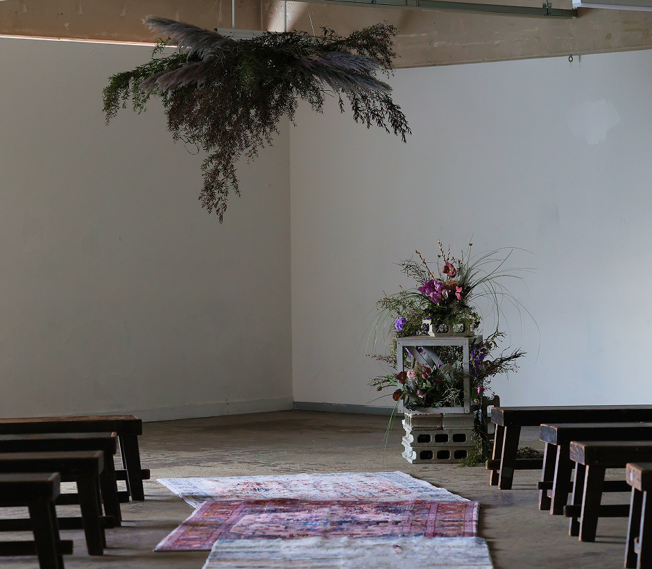 室内に設けられたシンプルな結婚式の祭壇と花飾り、並べられた木製ベンチ