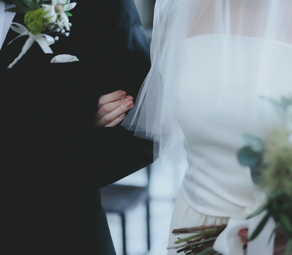 腕を組む新郎新婦の上半身、ブーケを持つ花嫁の手元