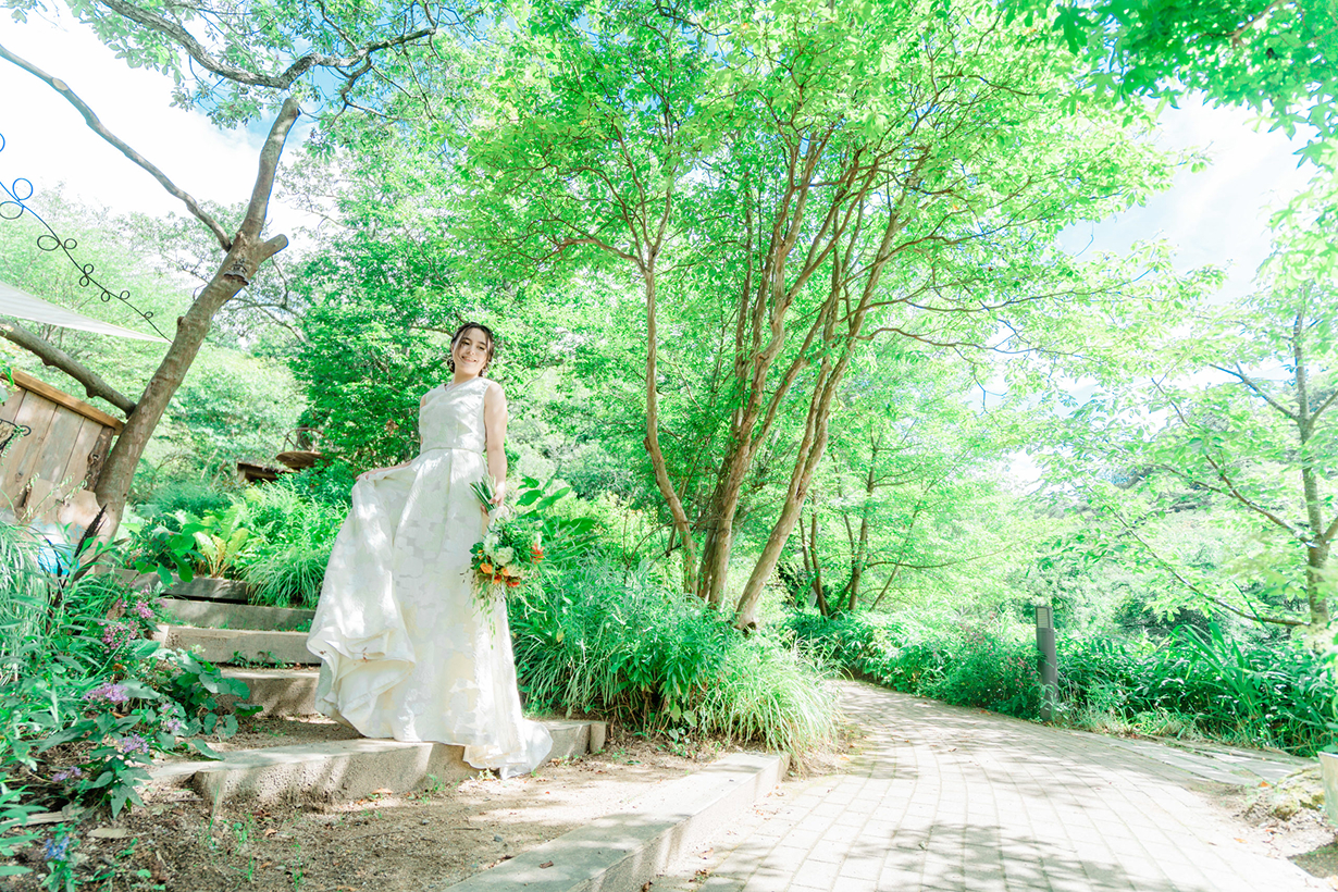 美しい森の中で花嫁がブーケを片手に歩く様子